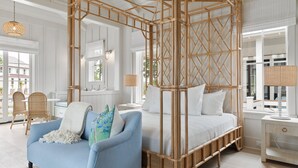 A bedroom with a four-poster bed, a blue armchair, and a wicker nightstand.