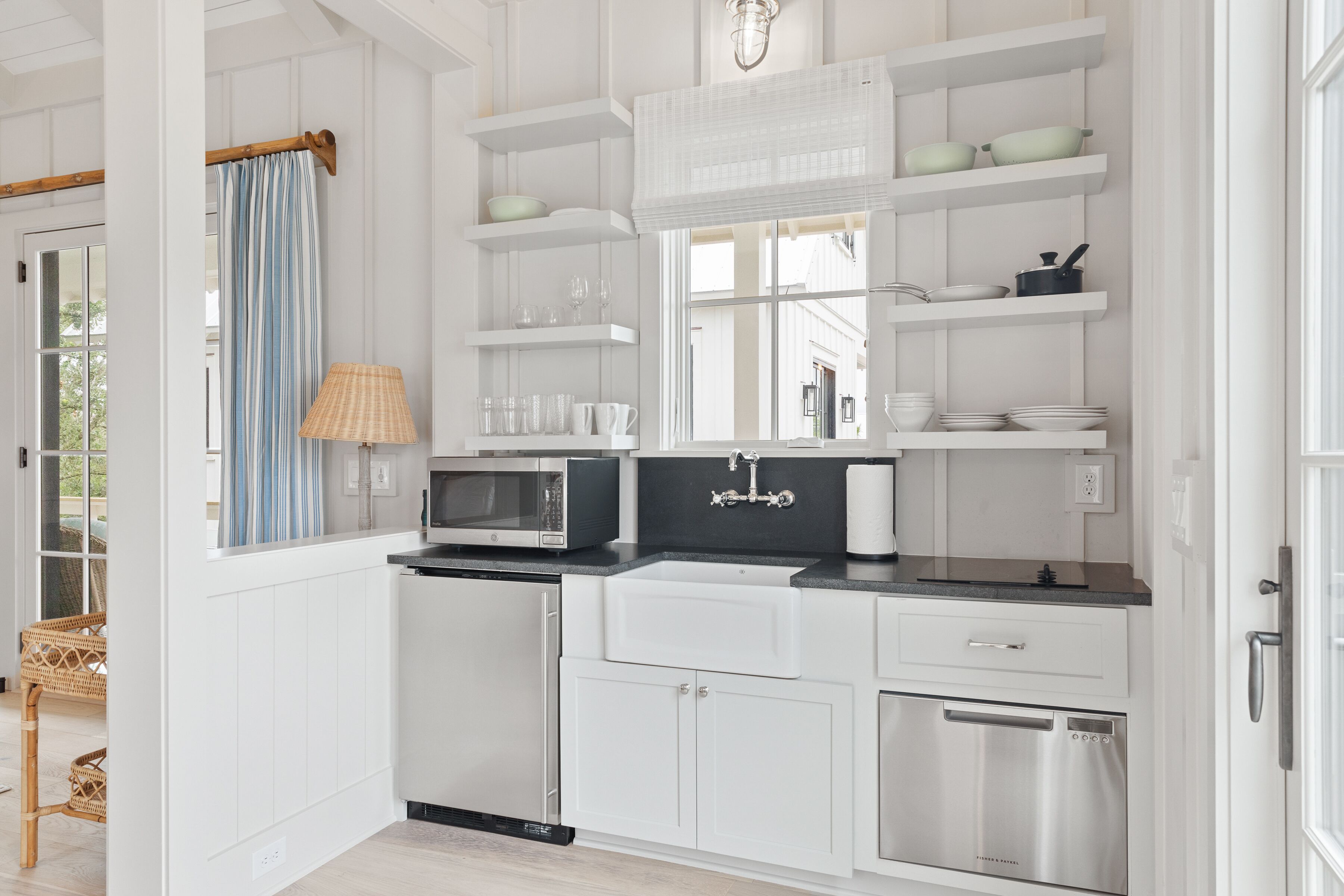 Una cocina moderna con armarios blancos, microondas, pileta y escurreplatos.