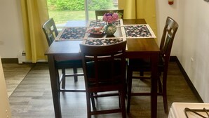 A dining area with a table set for two, chairs, a vase with flowers, and a fire extinguisher on the wall.