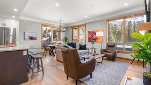 A modern living space with a kitchen, dining area, and seating area. - Spring Creek Vacations 2 BR Premier Condo 107A (Canmore)