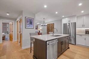 A modern kitchen with a central island, stainless steel appliances, and a dining area with patterned chairs.
