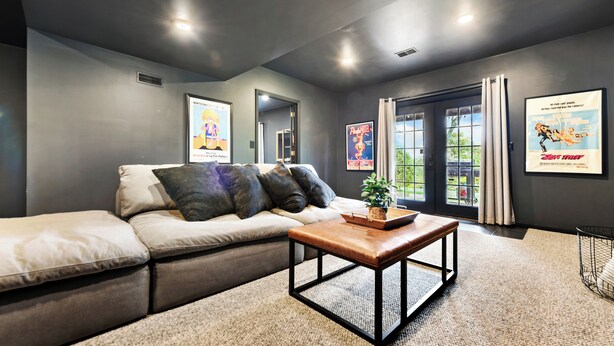 A modern living room with a sectional sofa, a coffee table, and framed movie posters on the walls. - Gorgeous Private Apartment (Aliquippa)