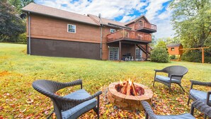A two-story house with a covered patio and a fire pit in the yard. - Gorgeous Private Apartment (Aliquippa)