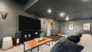 A modern living room with a flat-screen TV, a stone fireplace, and a large sofa. - Gorgeous Private Apartment (Aliquippa)