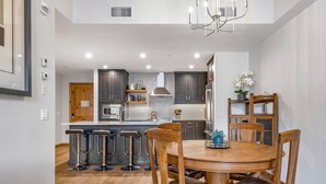 Una cocina moderna con armarios oscuros, una isla central y taburetes de bar.