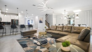 A modern living room with a sectional sofa, a glass coffee table, and a patterned rug.