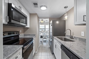 A modern kitchen with stainless steel appliances, granite countertops, and a view to the dining area.