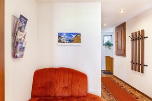 A hallway with a wooden door, a wall-mounted coat rack, and a framed picture.