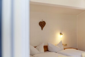 A hotel room with two beds, a wall-mounted light fixture, and a decorative wooden piece on the wall.