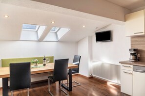 A modern kitchen with a built-in oven, a coffee machine, and a TV mounted on the wall.