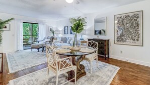 Un coin repas avec une table à plateau en verre, des chaises blanches et un ventilateur de plafond.