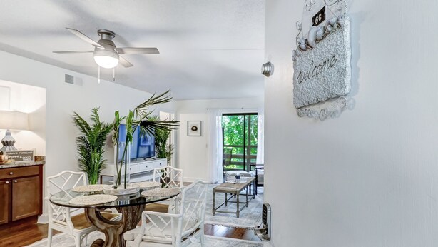 Un coin repas avec une table ronde, des chaises blanches et un ventilateur de plafond.