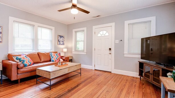 A living room with a brown leather sofa, a wooden coffee table, and a television on a wooden stand.
