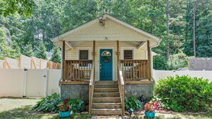 A small, single-story house with a front porch, a blue door, and a mailbox.