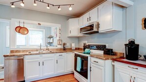 A modern kitchen with white cabinets, a stainless steel dishwasher, a built-in oven, and a microwave.
