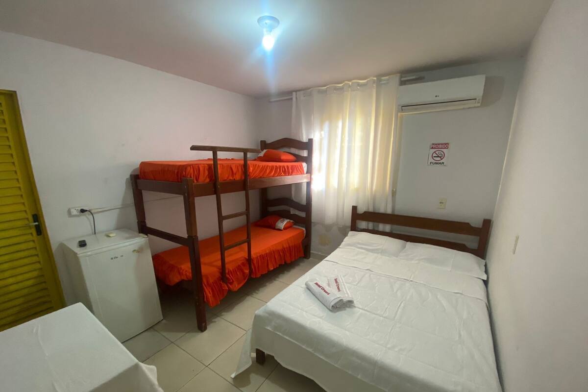 Un dormitorio con literas, una mesita de noche pequeña, un calentador y un equipo de aire acondicionado.