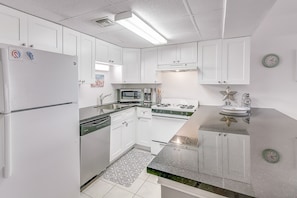 A modern kitchen with white cabinets, a refrigerator, microwave, stove, and a sink.