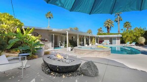 A modern outdoor pool area with a fire pit, lounge chairs, and a covered seating area. - Sunset Glamour - Enchanting Luxury Zen Retreat (Palm Springs)