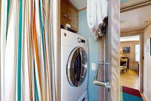 Laundry room with a front-loading washing machine, wooden cabinetry, and a towel hanging on the door.