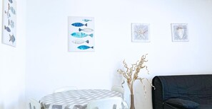Um quarto com uma mesa redonda, um sofá preto e obras de arte nas paredes, incluindo peixes e uma estrela-do-mar.