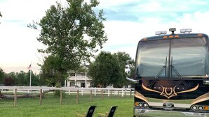 A bus parked on grass with two chairs in front. - Parkton Place Campsite #4 on farm with pond! (Parkton)