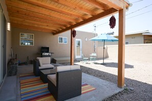 Relax in a cozy outdoor space with a sofa, wicker chair, and small table.