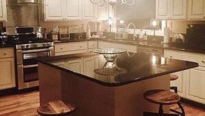Una cocina con una isla central, electrodomésticos de acero inoxidable y armarios blancos.