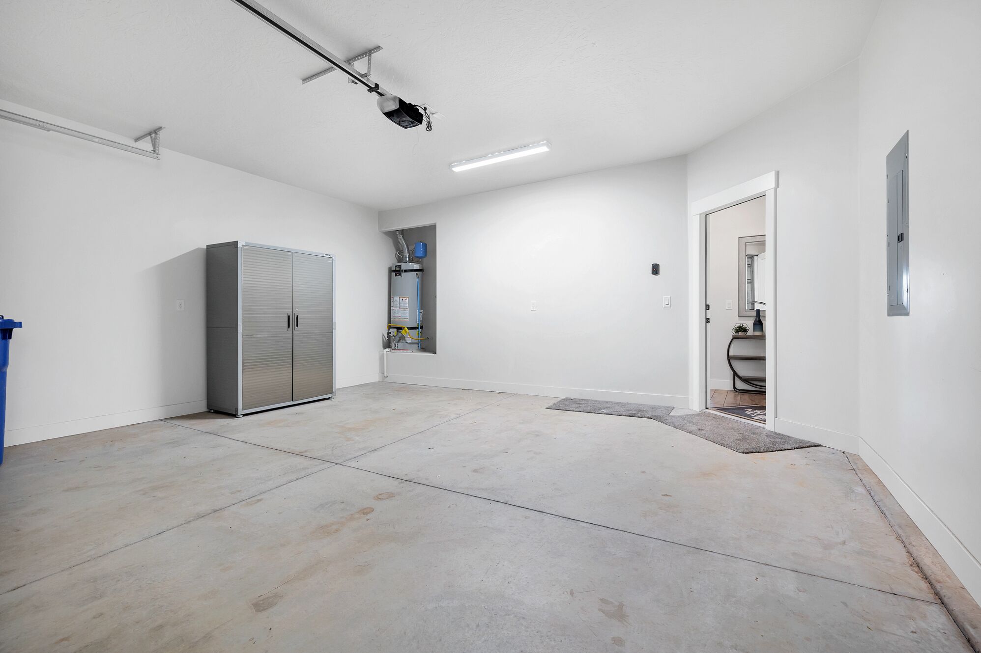 A spacious, well-lit room with a large cabinet, a water heater, and a door leading to another area.