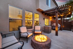Eine Terrasse mit Feuerstelle, Sitzgelegenheiten und einer Pergola.