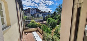 Un patio con una pérgola, una pequeña piscina y vistas de edificios circundantes.