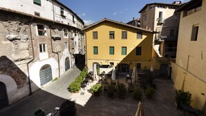 Un patio con mesas al aire libre, rodeado de edificios de arquitectura histórica.