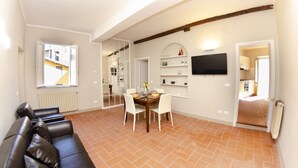 Amplia sala de estar con una mesa de comedor, un sofá y un televisor montado en la pared.