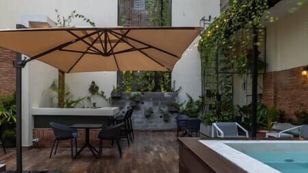 An outdoor patio area with a pool, seating, and a staircase leading to a higher level. - Loft 101 - w/balcony - Daily Cleaning (Santo Domingo)