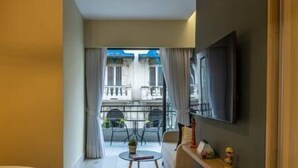 A modern hotel room with a balcony, a flat-screen TV mounted on the wall, and a small round table with a chair. - Loft 101 - w/balcony - Daily Cleaning (Santo Domingo)