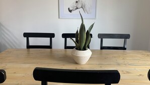 A dining table with a potted plant in the center, surrounded by black chairs. - Cozy Townhome Gathering Spot (Clinton)