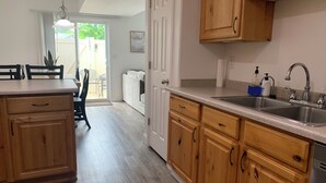 A kitchen with wooden cabinets, a double sink, and a dining area with a table and chairs. - Cozy Townhome Gathering Spot (Clinton)