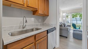 Una cocina con armarios de madera, un lavamanos de acero inoxidable y un lavavajillas.