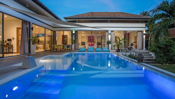 Ein modernes Haus mit Schwimmbad, Glastüren und einer Terrassenfläche.