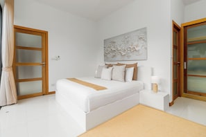 A bedroom with a bed, bedside table, lamp, and a large floral artwork on the wall. - Modern 4BR Pool Villa Virginie Naiharn (Rawai)