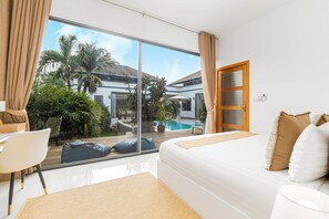 A modern bedroom with a large window, a bed, and a view of a swimming pool and palm trees. - Modern 4BR Pool Villa Virginie Naiharn (Rawai)