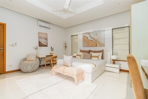 A modern bedroom with a bed, bedside table, lamp, and a desk with chair.