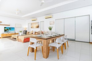 A modern living room with a dining area, white furniture, and artwork on the walls.