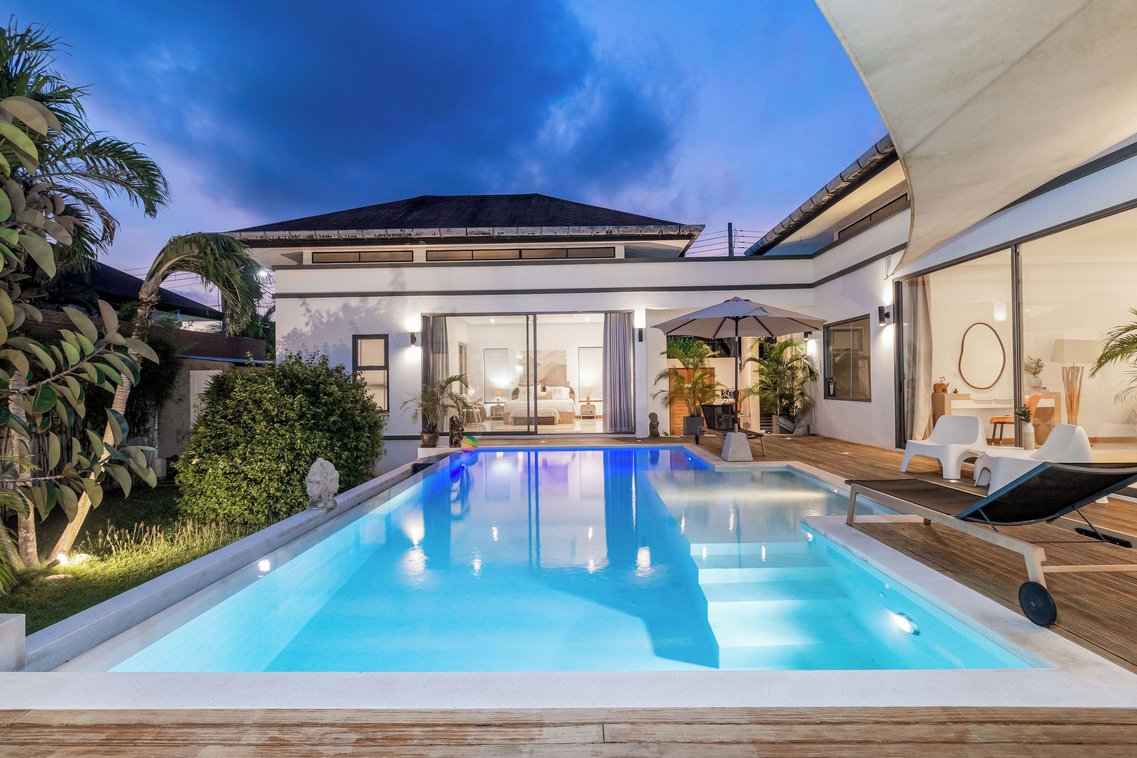 Un espace piscine moderne avec une piscine à l’eau d’un bleu limpide, entourée d’une terrasse en bois et de chaises longues.