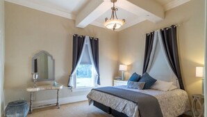 Een slaapkamer met een bed, nachtkastjes, een spiegel en een kroonluchter.