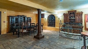 Quarto com área de bar, armários de madeira e mesa de jantar com cadeiras.