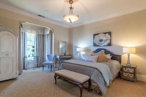 A bedroom with a bed, bedside tables, a desk, a chair, and a bench.