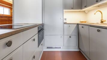 Een compacte keuken met inbouwapparatuur, een raam en een houten plafond.