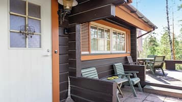A wooden cabin with a porch, a door with a window, and outdoor seating.