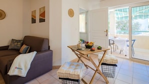 Un salon avec un canapé, une petite table sur laquelle sont disposés des fruits, et une vue sur l’extérieur.