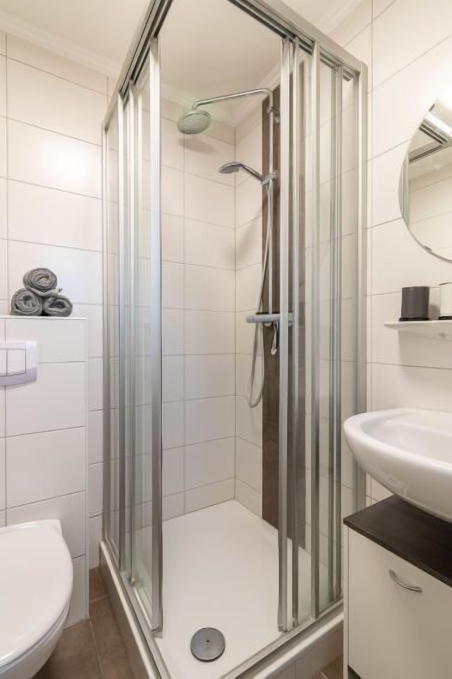 Une salle de bain moderne avec une douche à parois de verre, un lavabo blanc et des toilettes.